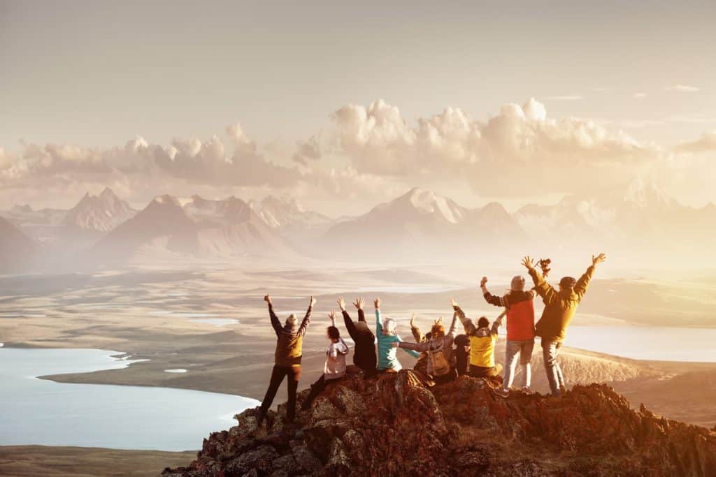 Groupe d'amis levant les bras au sommet d'une montagne