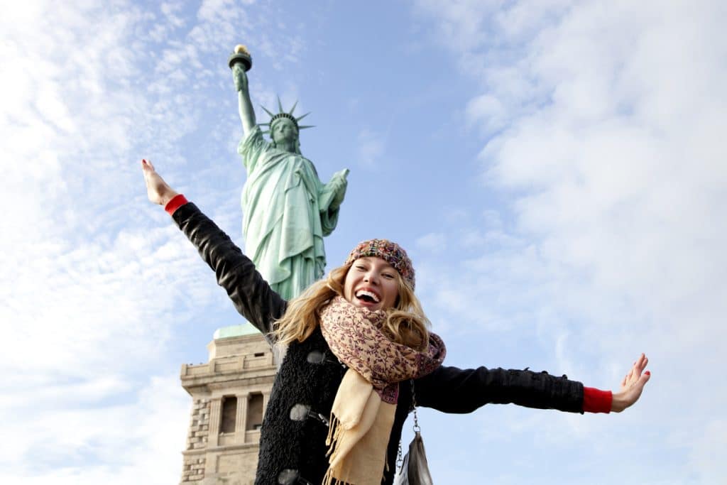 Jeune femme heureuse devant la statue de la liberté