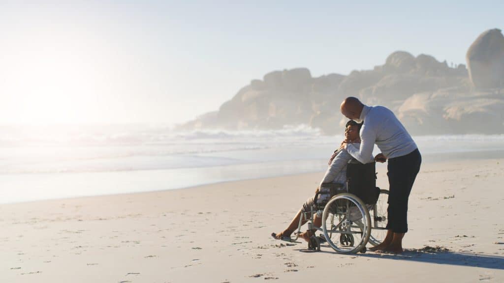 Homme et femme en fauteuil roulant sur la plage