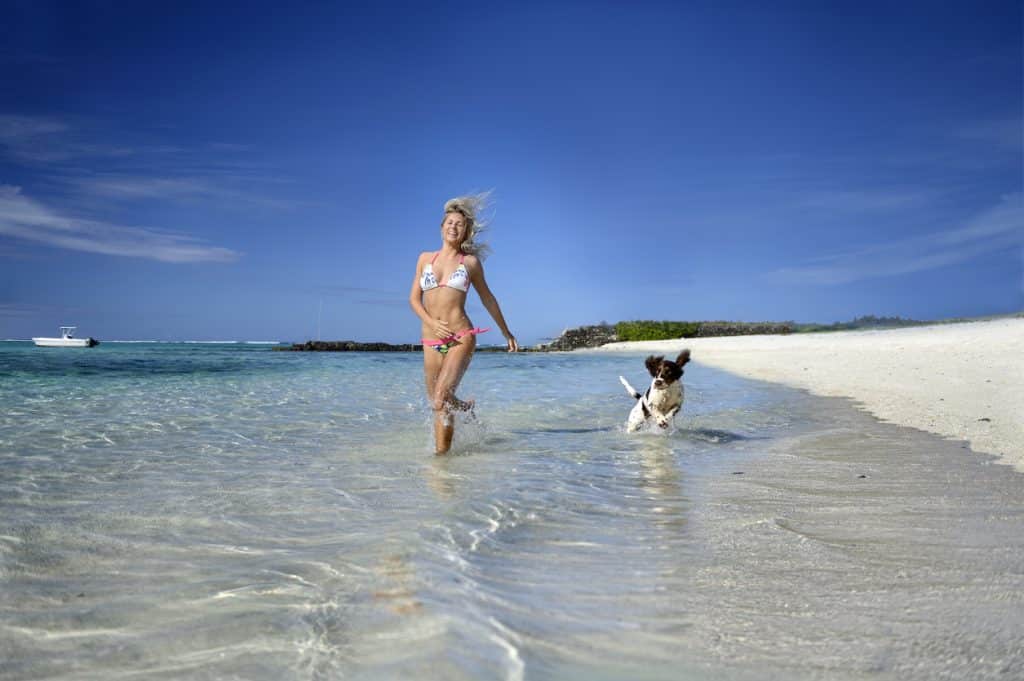 Femme qui court sur le bord de plage avec son chien
