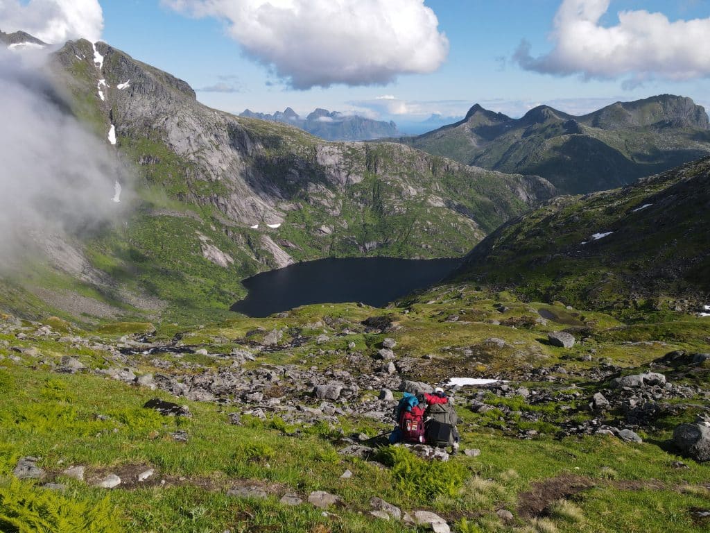 Couple assis au milieu des montagnes durant une randonnée dans les îles Lofoten
