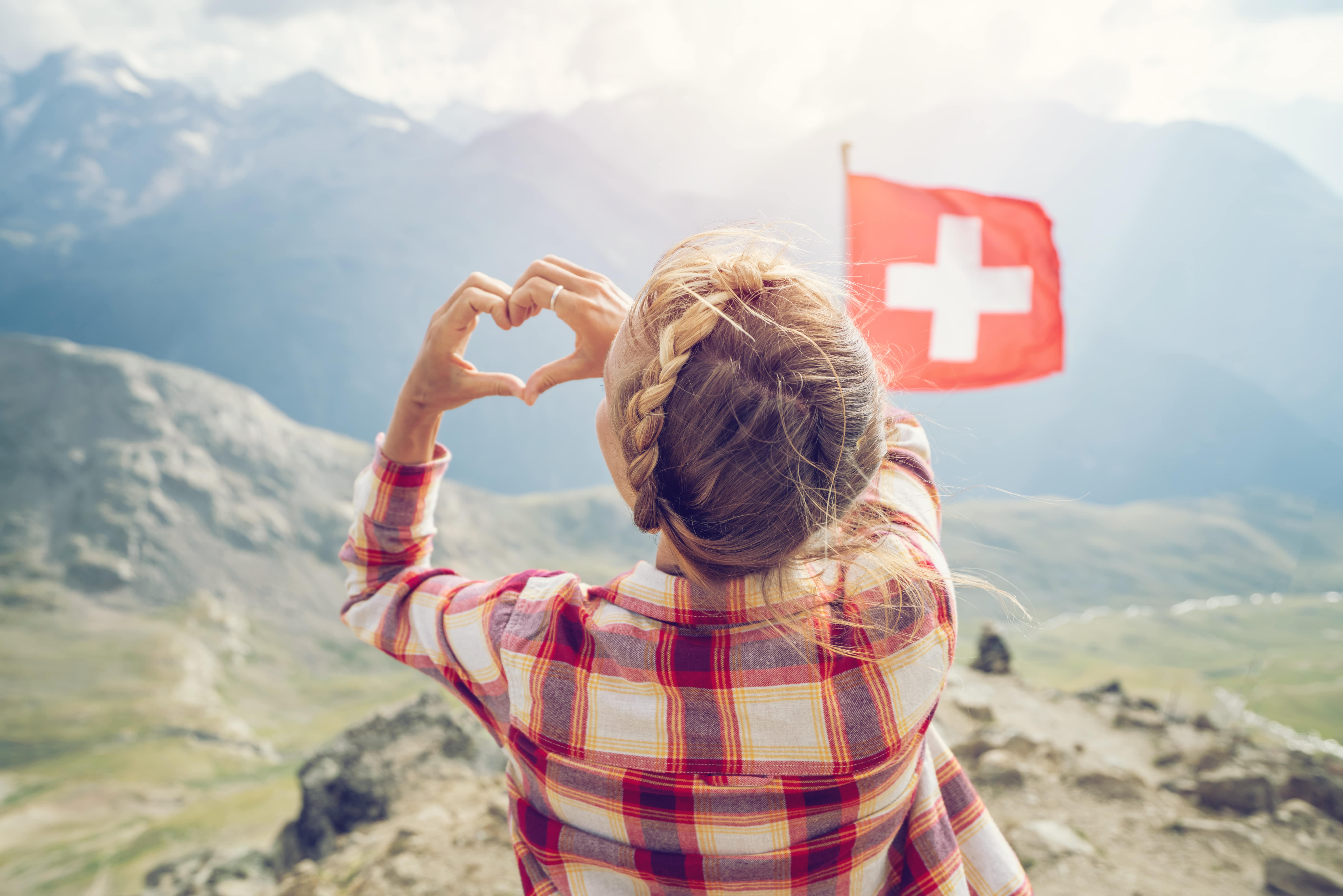 Jeune femme faisant un cœur avec ses mains au sommet des Alpes Suisses