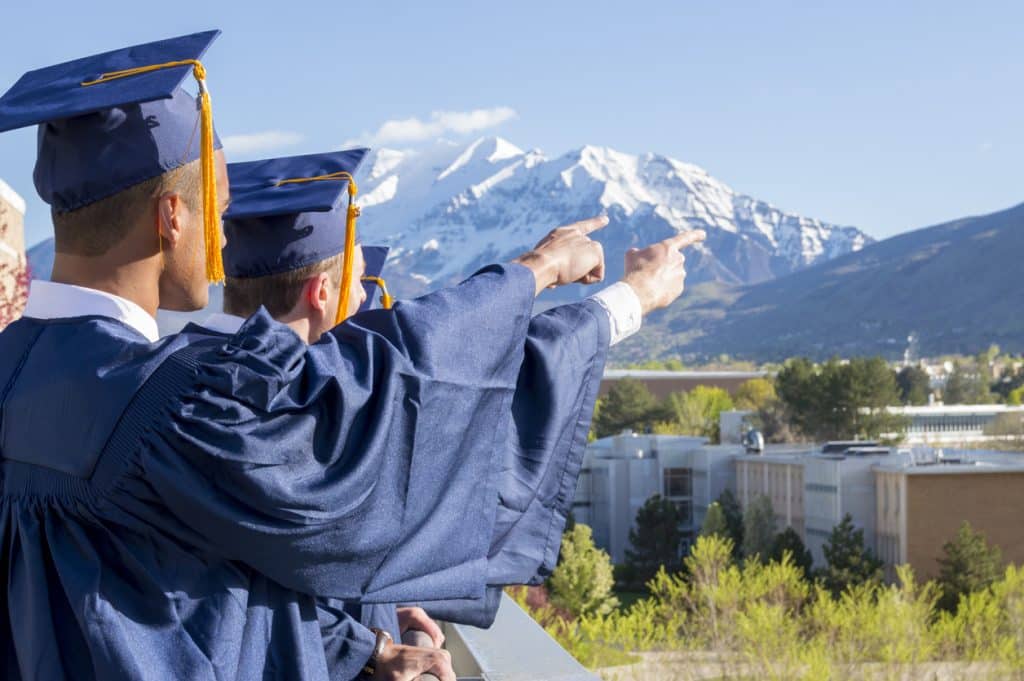Jeunes diplômes en habit de cérémonie regardant vers les montagnes