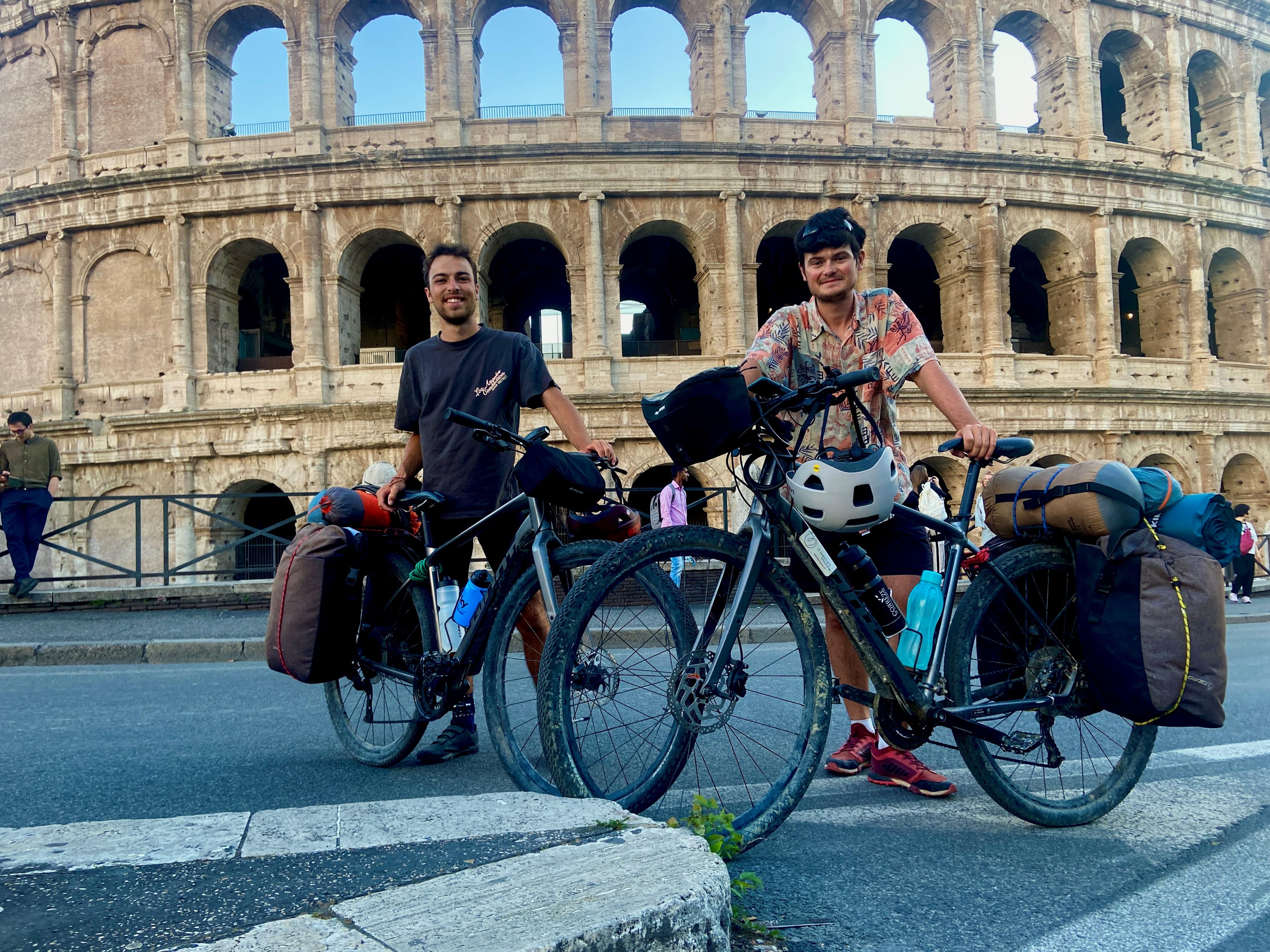 Deux jeunes hommes à vélo devant le Colisée de Rome