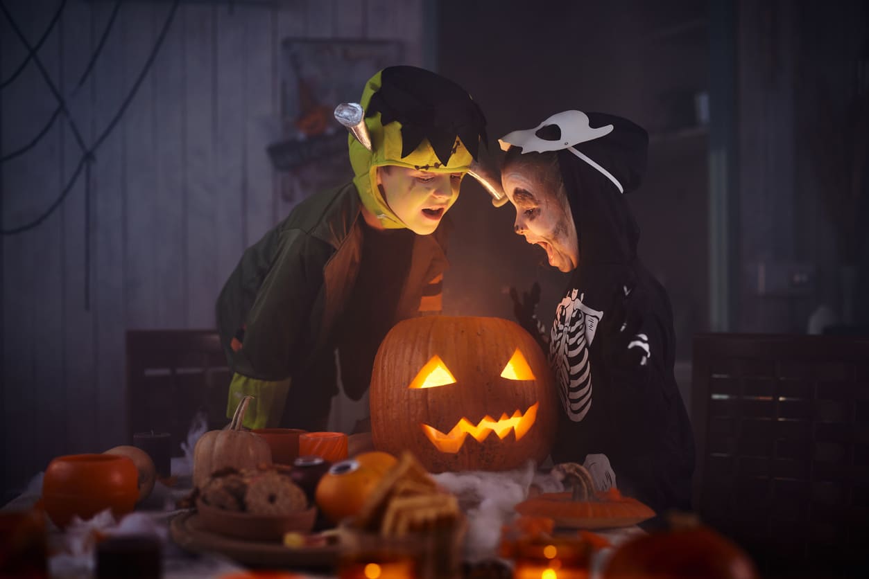 Deux enfants déguisés regardant à l'intérieur d'une citrouille halloween 