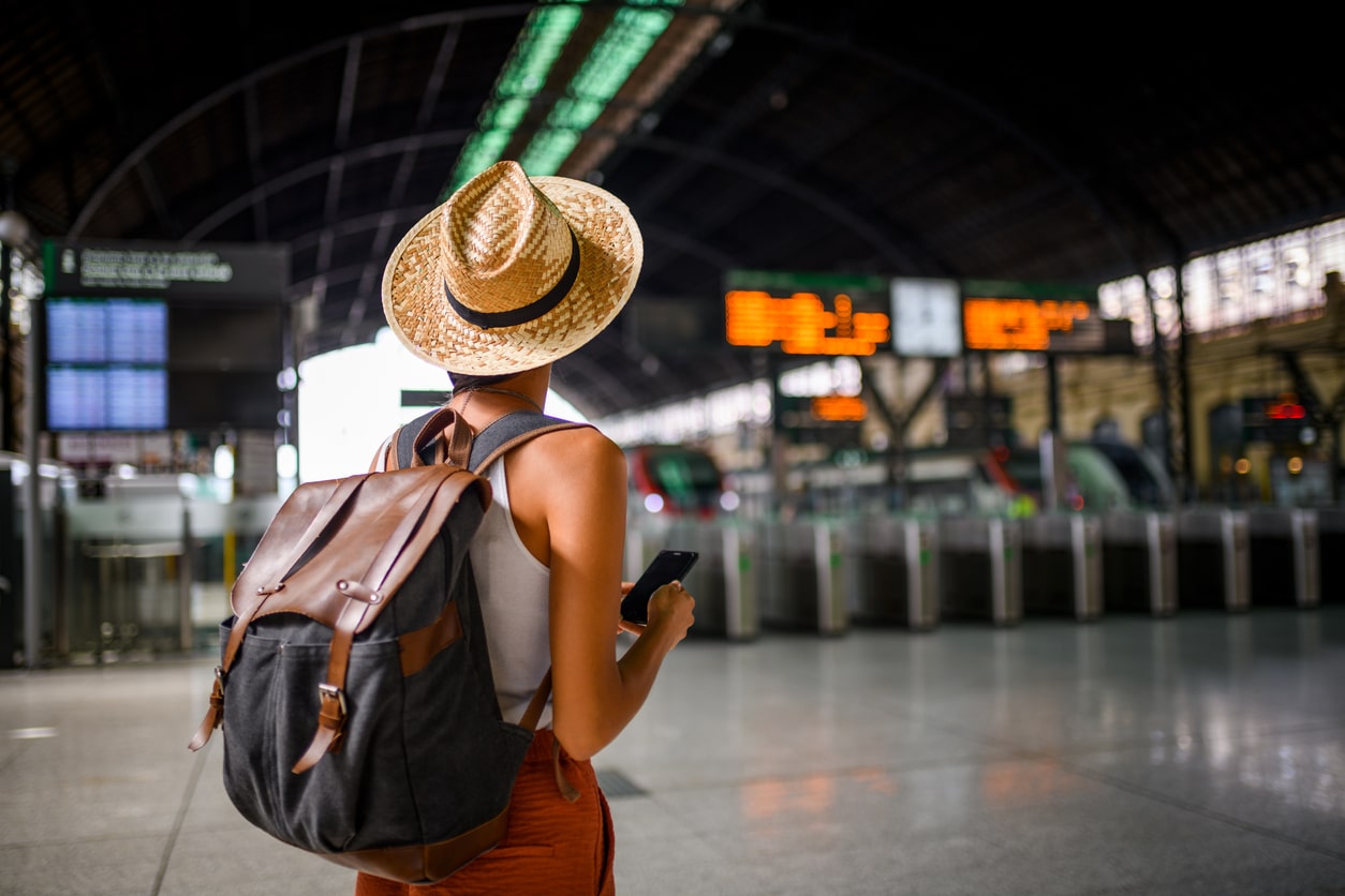 Femme seule sur son téléphone devant les quais d'une gare