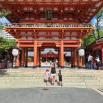 Une mère tenant la main de ses deux enfants devant un temple japonais