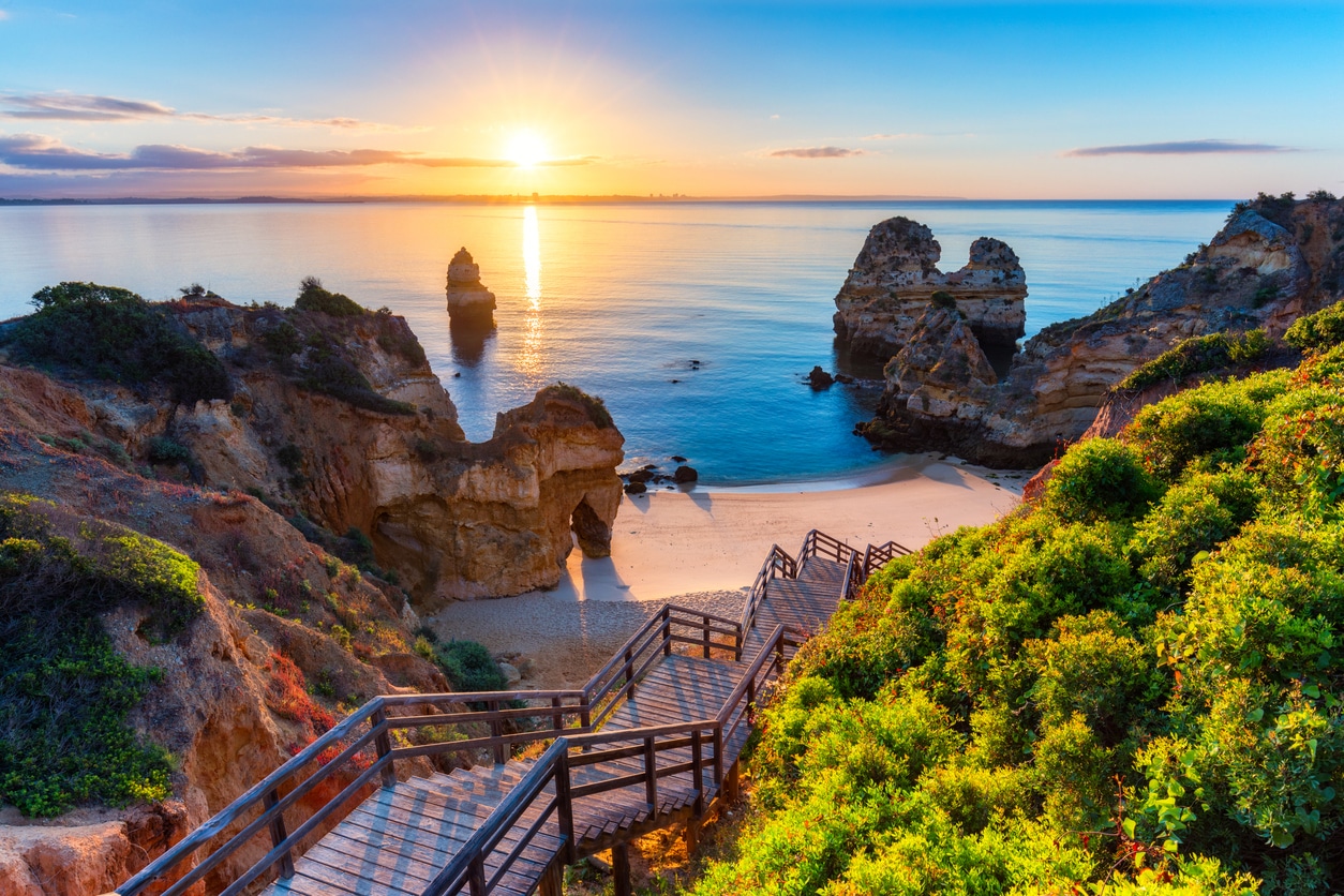Escaliers en bois descendant sur une plage paradisiaque au coucher de soleil