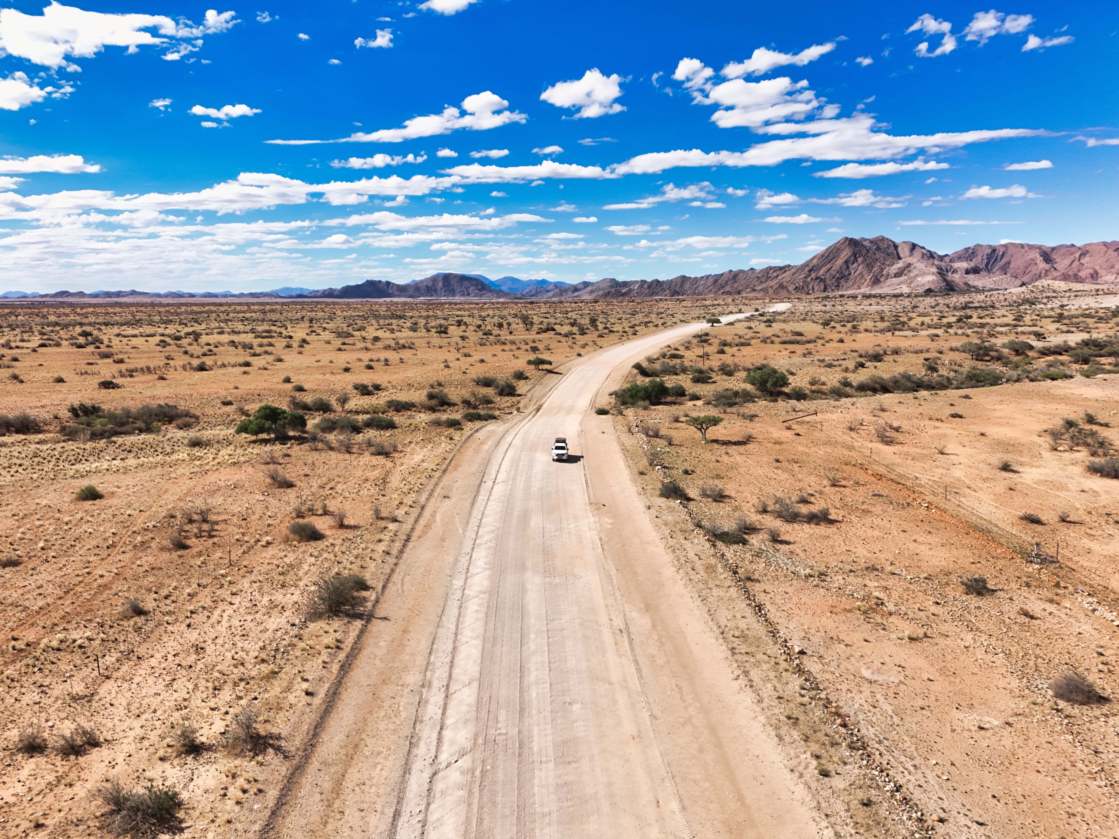 Vue aérienne d'un 4x4 qui roule sur une route dans un désert