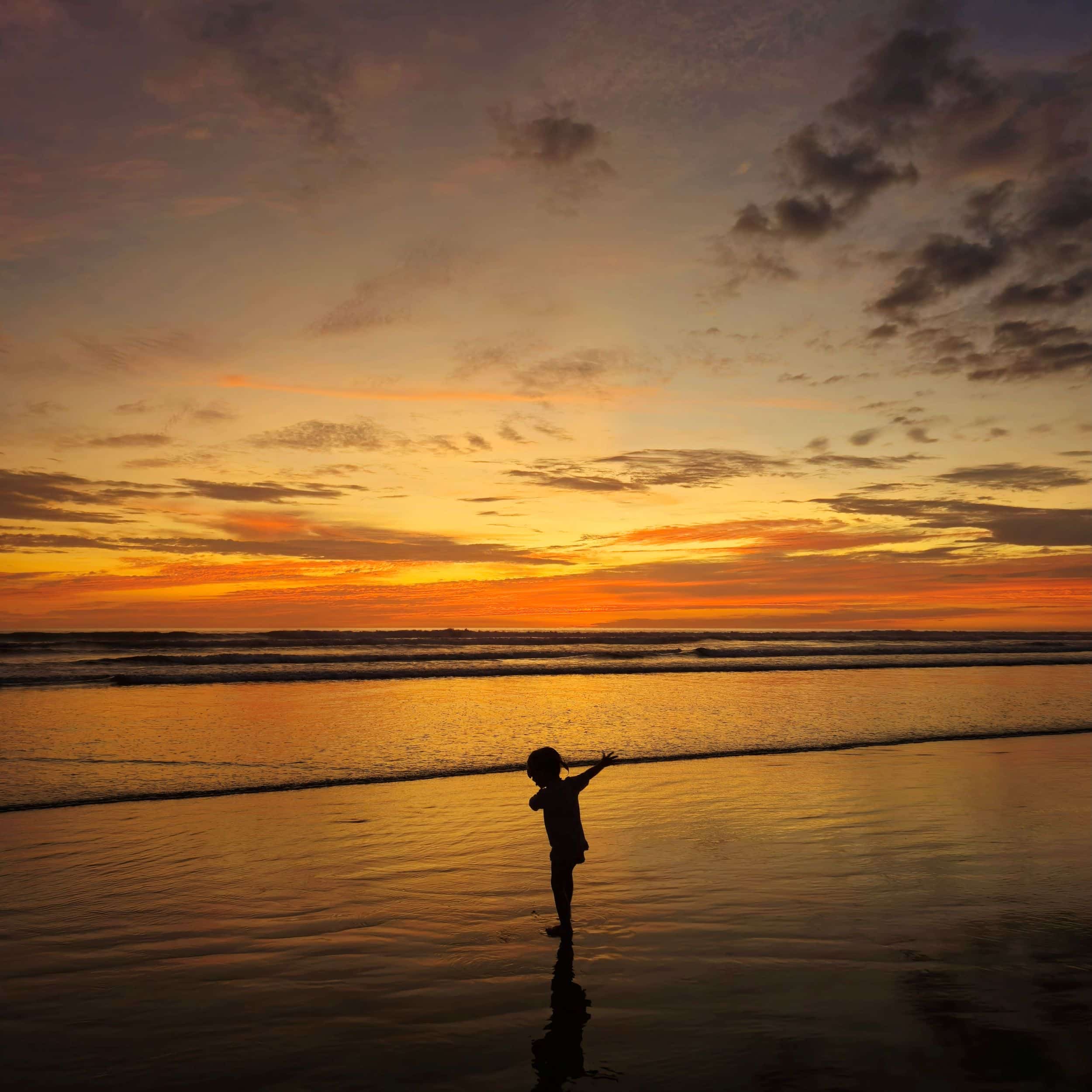 Petite fille qui danse sur la plage au coucher du soleil