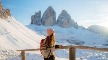Jeune femme en haut de la montagne admirant les sommets enneigées de Tre Cime