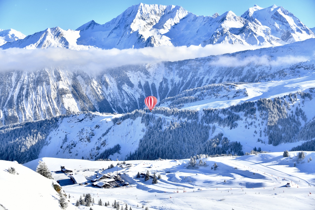 Montgolfière rouge au-dessus des pistes de ski enneigées