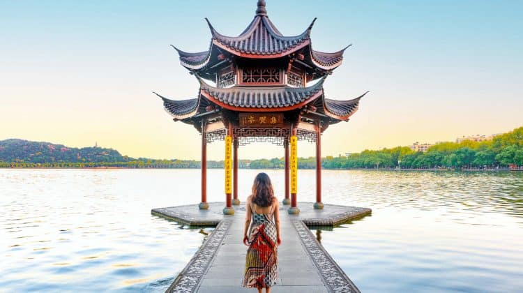 Femme devant un temple chinois face au lac