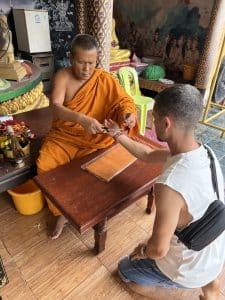 Moine bouddhiste qui met un bracelet à un jeune touriste